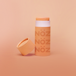 Load image into Gallery viewer, Opened orange Nöz sunscreen stick with cap leaned up against left side of sunscreen stick.
